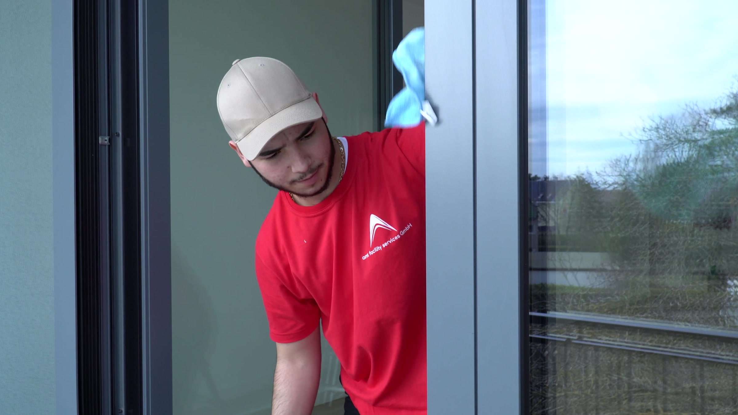 Glasreinigung Berlin: Mitarbeiter der AMT multiservices reinigt Rahmen und Scheibe einer Fensterfront